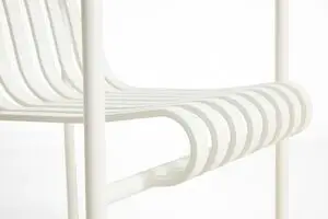 Nærbillede af en cremehvid spisebordsstol med lameldesign og synlige armlæn.