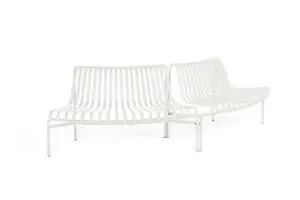 To hvide bænke i moderne design med slatted ryg og sæde, hver med fire ben, vinklet mod hinanden.