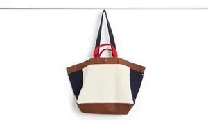 Medium weekendtaske i creme med brune, mørkeblå og røde detaljer. To håndtag og rummeligt design.