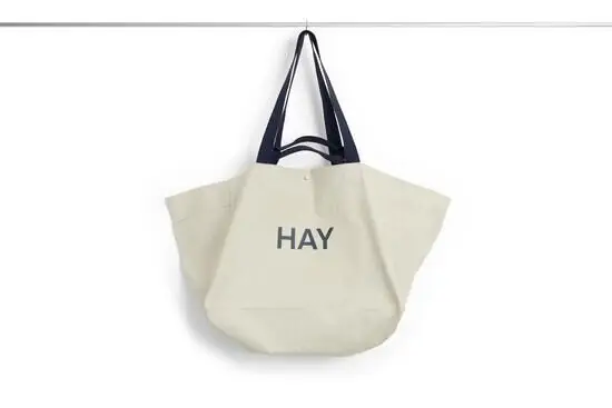 Stor grå weekendtaske med sort håndtag og teksten "HAY" på forsiden.