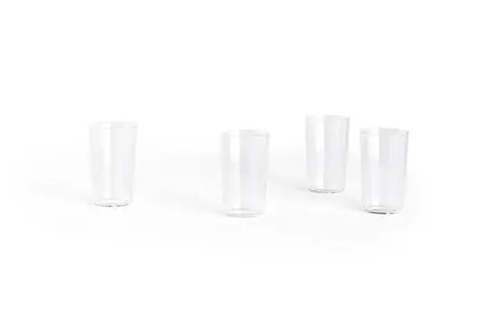 Fire klare drikkeglas, enkle og cylindriske, står spredt på en lys baggrund.