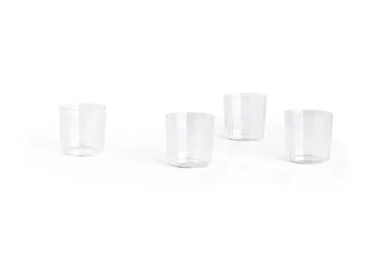 Fire klare glas med en enkel, cylindrisk form står spredt på en lys overflade.