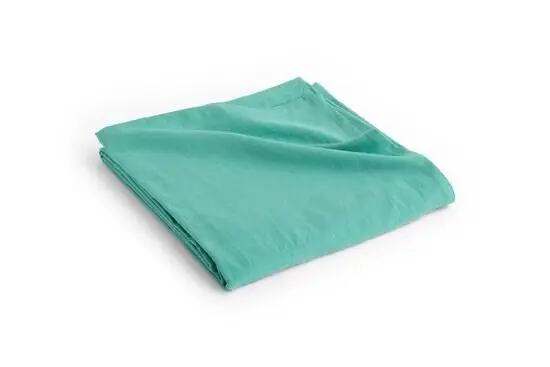 En foldet sengetæppe i smaragdgrøn farve. Stoffet ser glat og blødt ud, med en enkel stil.