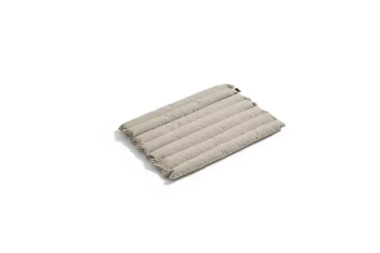 Beige, quiltet sædehynde med vandrette syninger. Rektangulær og blød i udseende.