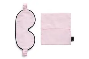 Blød pink sovemaske med sort kant og elastisk bånd, inkl. matchende opbevaringspose.