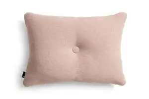 Rektangulær pude i blød pink med knap i midten og synligt mærkat på siden.