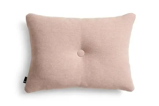 Rektangulær pude i blød pink med knap i midten og synligt mærkat på siden.