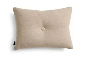 Rektangulær beige pude med tekstur, central knap, afrundede kanter og Hay-mærke på siden.