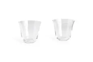 To små, klare tumblerglas med buet design, står side om side. Sæt af 2 fra Hay.