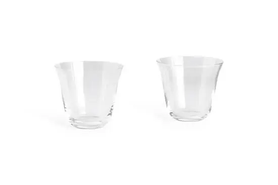 To små, klare tumblerglas med buet design, står side om side. Sæt af 2 fra Hay.