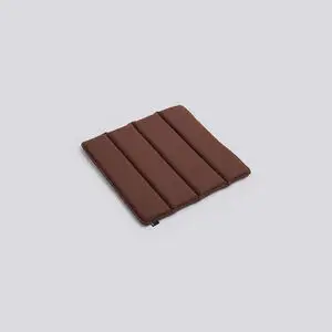 Rødbrun quiltet sædepude med parallelle syninger, der giver et segmenteret udseende.