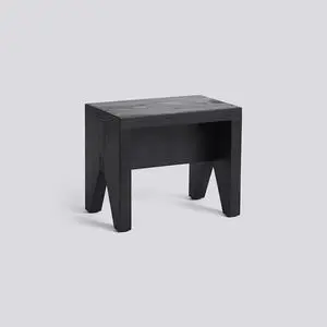 Sort, rektangulær skammel med fladt sæde og brede ben i omvendt "V"-form. Minimalistisk design.