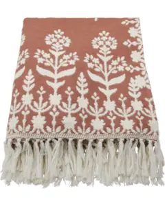 Tæppe med hvidt blomstermønster på terracotta baggrund og frynser langs kanten.
