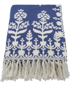 Blåt tæppe med hvidt blomstermønster og frynser, foldet sammen.