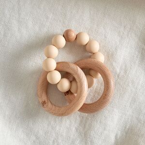 To træ-ringe forbundet af beige perler, danner en glat bidering til babyer.