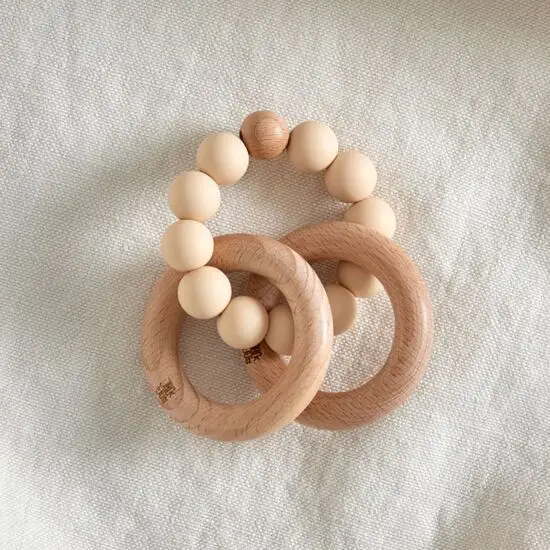 To træ-ringe forbundet af beige perler, danner en glat bidering til babyer.