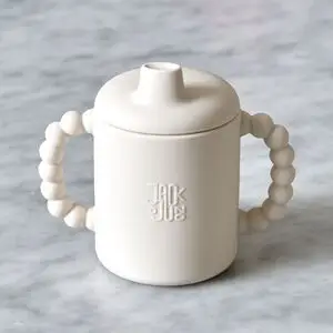 Cremefarvet tudekop med boblegreb, tudlåg og "Jack o Juno" logo på forsiden.