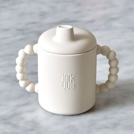 Cremefarvet tudekop med boblegreb, tudlåg og "Jack o Juno" logo på forsiden.