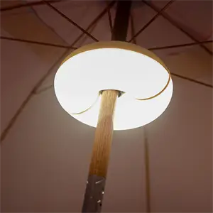 Rund lampe fastgjort til parasolstang, lyser op.