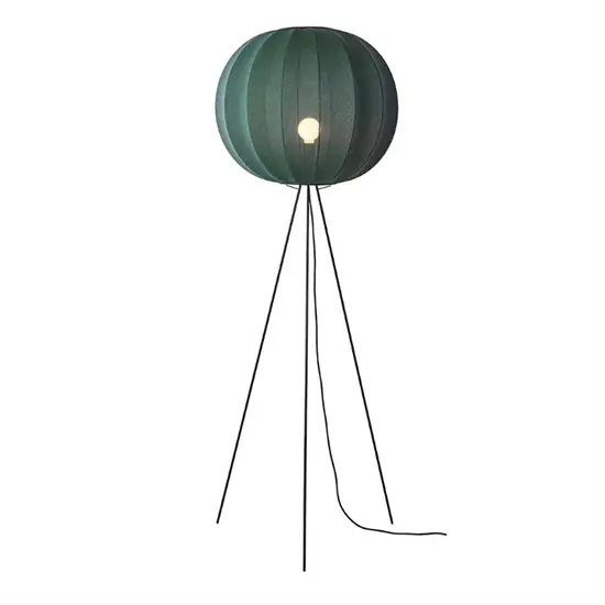 Gulvlampe med rund, ribbet, dybgrøn skygge og tynde ben.