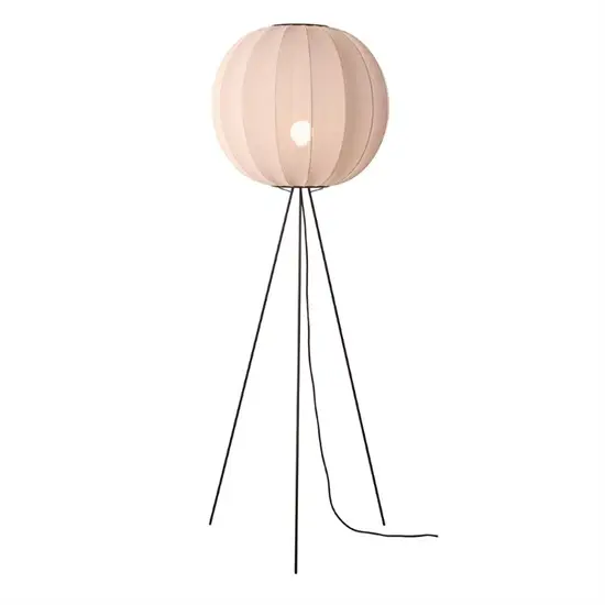 Gulvlampe med rund, lys skygge og tre sorte ben i metal, skaber et moderne og minimalistisk udtryk.