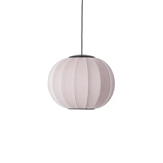 Rund pendellampe i lys pink med stribet overflade, hængt op med sort ledning.