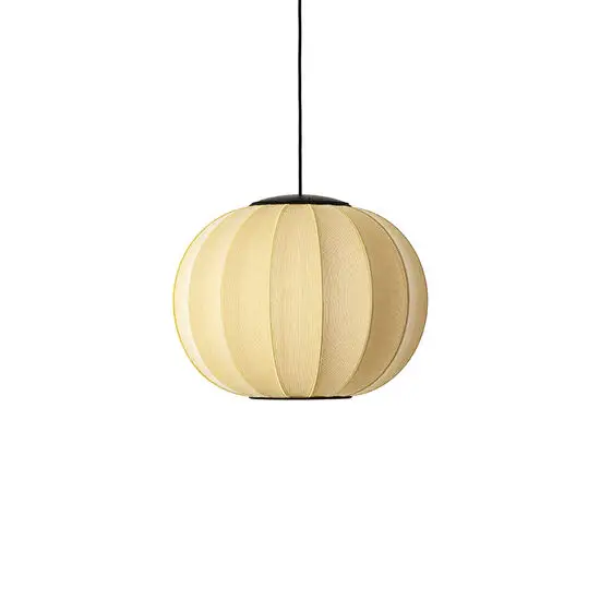 Rund, lys beige pendellampe med lodrette striber, hængende fra sort ledning mod neutral baggrund.