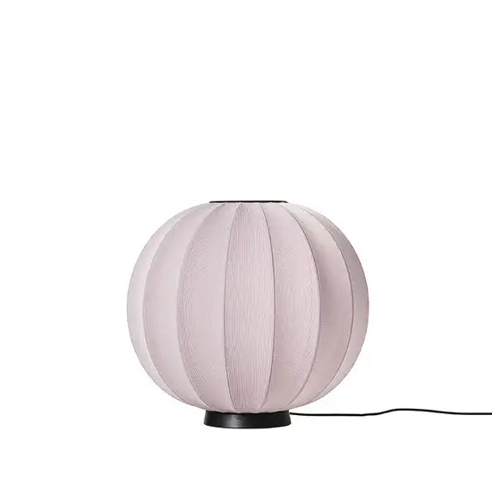 Rund lyserød lampe med tekstur, sort base. Blød, moderne æstetik.