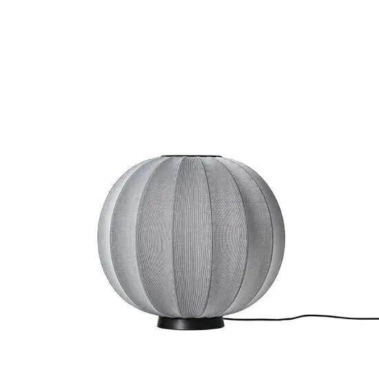 Sølvfarvet rund lampe med strikket overflade og sort base. Blød form, elegant design.