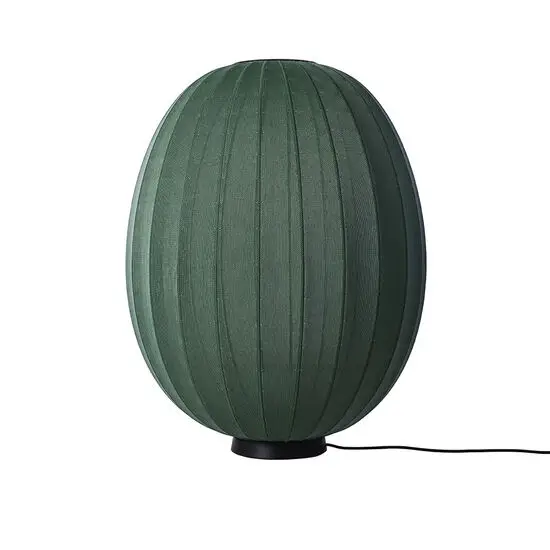 Oval, høj lampe i mørkegrøn med strikket overflade, sort base og synlig ledning.