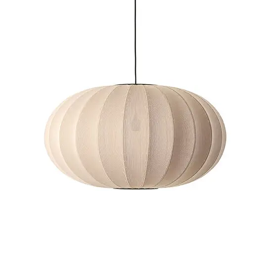 Oval lampe i lys beige med strikket overflade og sorte ledning. Vertikale striber ses tydeligt.
