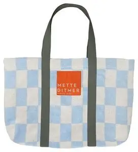 Strandtaske med lys blå/hvid tern, mørke håndtag og rød label med "METTE DITMER".