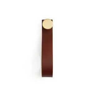 Rund metalkrog med lodret læderstrop i minimalistisk design.
