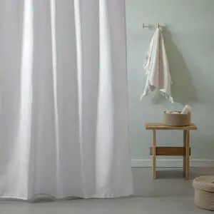 Hvidt badeforhæng med vaffelstruktur hænger i badeværelse. Mål: 180x200 cm.