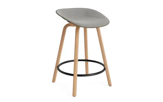 Barstol med buet sæde i søgrøn, lyse træben og sort fodstøtte, moderne design.