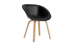Sort polstret stol med buet ryg og sæde, lyse træben. Normann Copenhagen Mat Armchair.