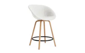 Hvid polstret barstol med begeben, buede ben og sort fodstøtte fra Normann Copenhagen.