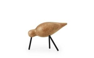 Træfugl med rund krop og spids hale på to sorte ben. Minimalistisk design i mellemstørrelse.