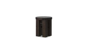Mørkebrun skammel fra Normann Copenhagen med rundt sæde og tre tykke ben i minimalistisk stil.