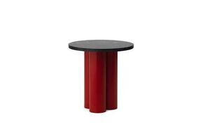Rundt bord med sort bordplade og lys rød base, tre cylindriske ben i moderne design.