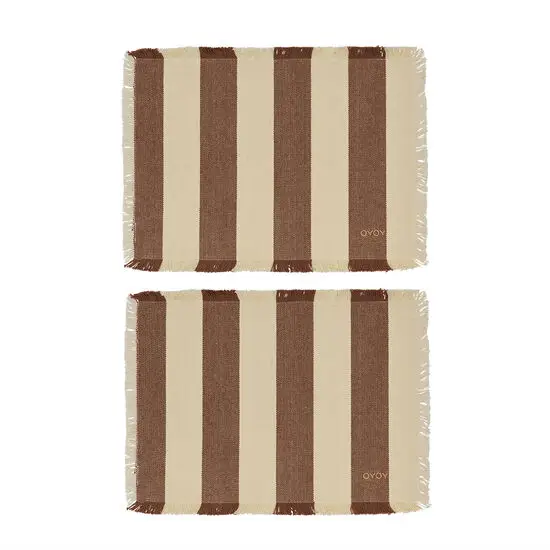 To rektangulære dækkeservietter med striber i lys beige og brun, frynser og "Oyoy" i hjørnet.