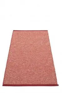 Rektangulært mørkerødt tæppe med små lyse romber og en mærkat i hjørnet.