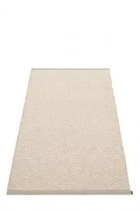 Rektangulært tæppe i lys neutral farve med subtilt mønster og lille mærke i hjørnet.