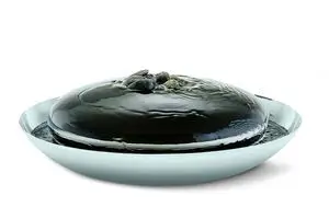 Rund vandfontæne med vand, der strømmer over en reflekterende kuppel med dekorative sten.