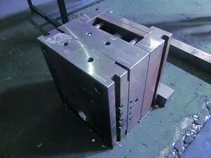 Metallisk rektangulær blok med huller og "Philippi" indgraveret, på ru overflade.