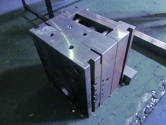Metallisk rektangulær blok med huller og "Philippi" indgraveret, på ru overflade.