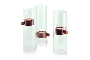 Tre cylindriske lysestager med transparent ydre og mørke dele, der holder lysene svævende.
