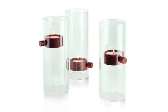 Tre cylindriske lysestager med transparent ydre og mørke dele, der holder lysene svævende.