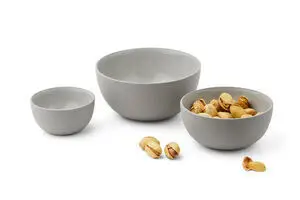 Sæt med tre skåle i faldende størrelse, den ene fyldt med pistacienødder. Enkel og glat design.