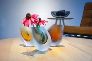 Asymmetrisk brun vase med pink blomster på træbord, velegnet til dekoration.